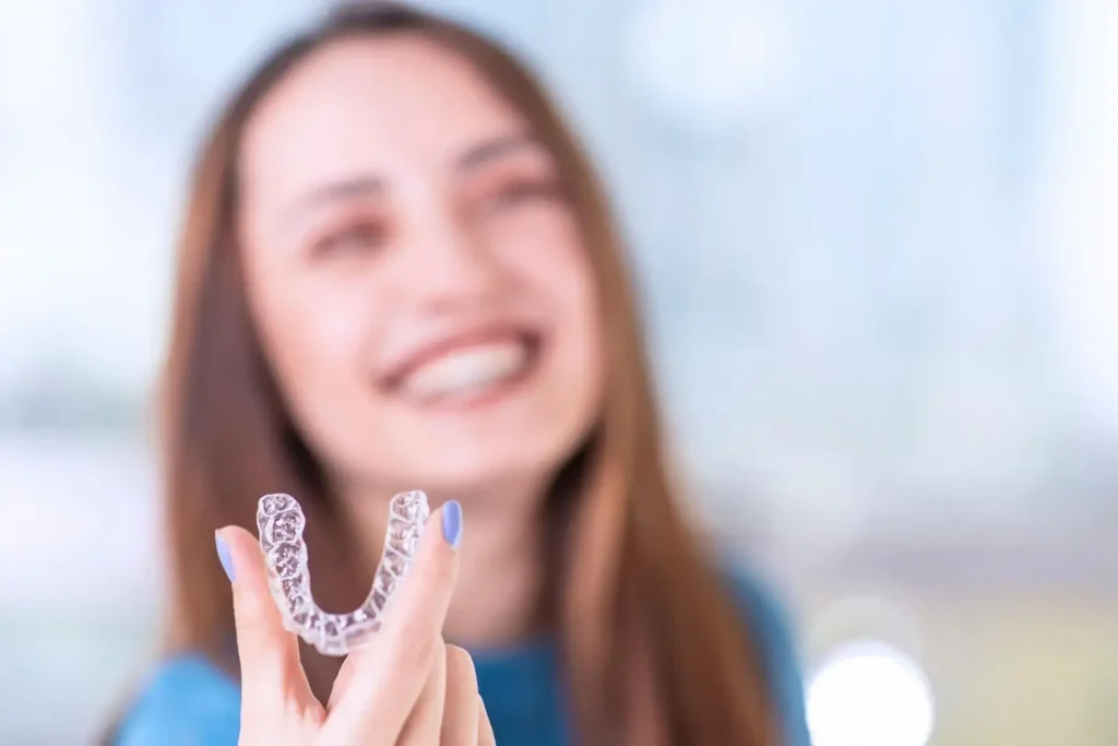 Mujer mostrando alineadores invisibles en clínica dental Doctores Ya